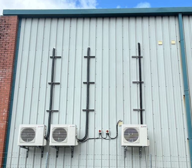 Three Mitsubishi air conditioning condensers installed on a commercial building