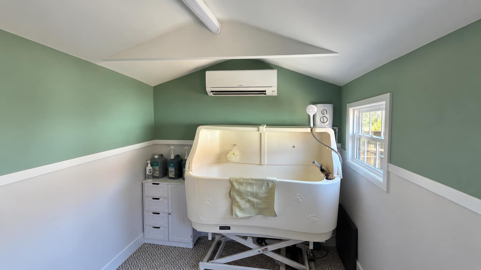 Wall-mounted air conditioning unit installed in a dog grooming studio